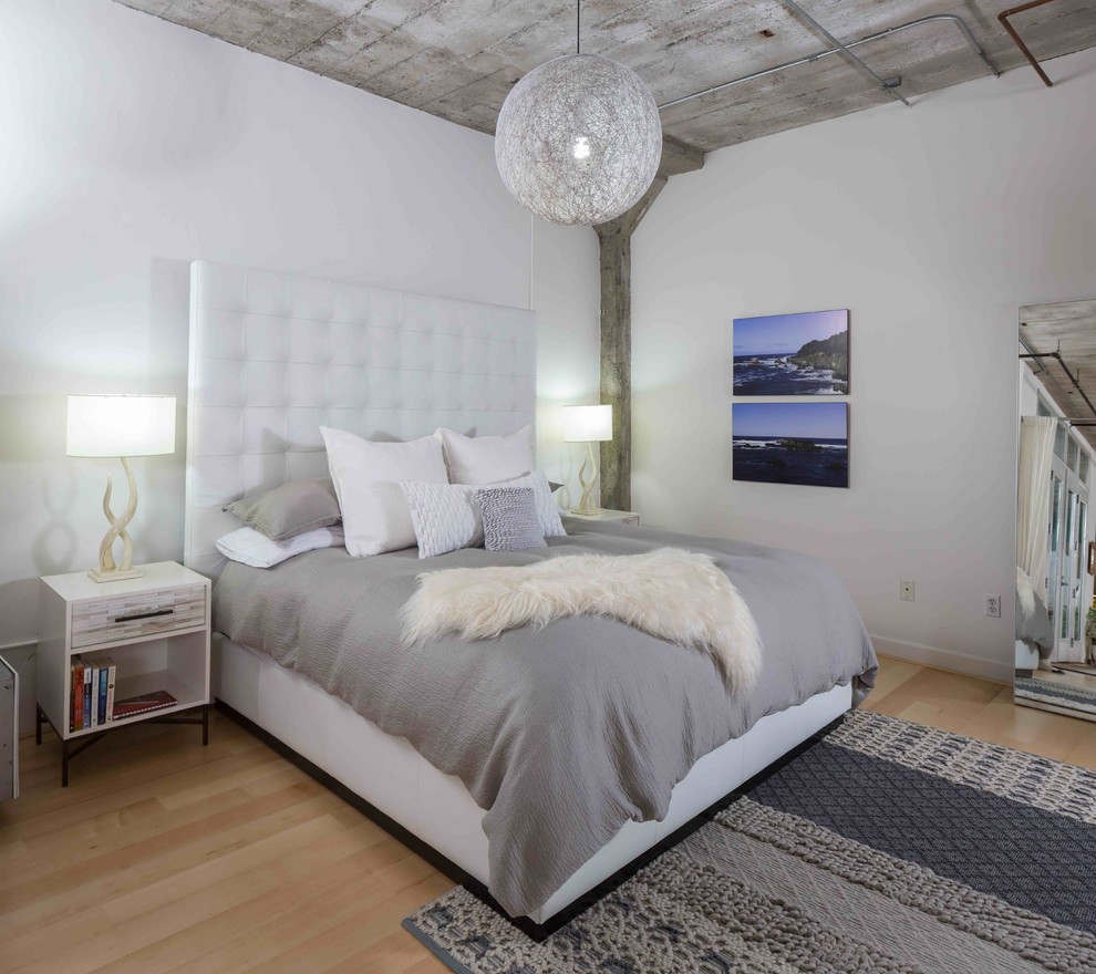 На фото: спальня в стиле лофт с белыми стенами и светлым паркетным полом с