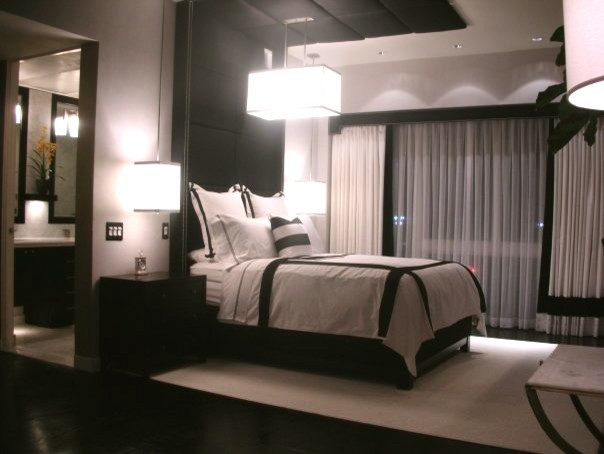Cette image montre une grande chambre parentale minimaliste avec un mur gris, un sol en contreplaqué et un sol noir.