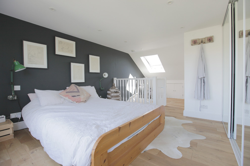 Photo of a medium sized contemporary master bedroom in London with grey walls, light hardwood flooring, beige floors and a feature wall.