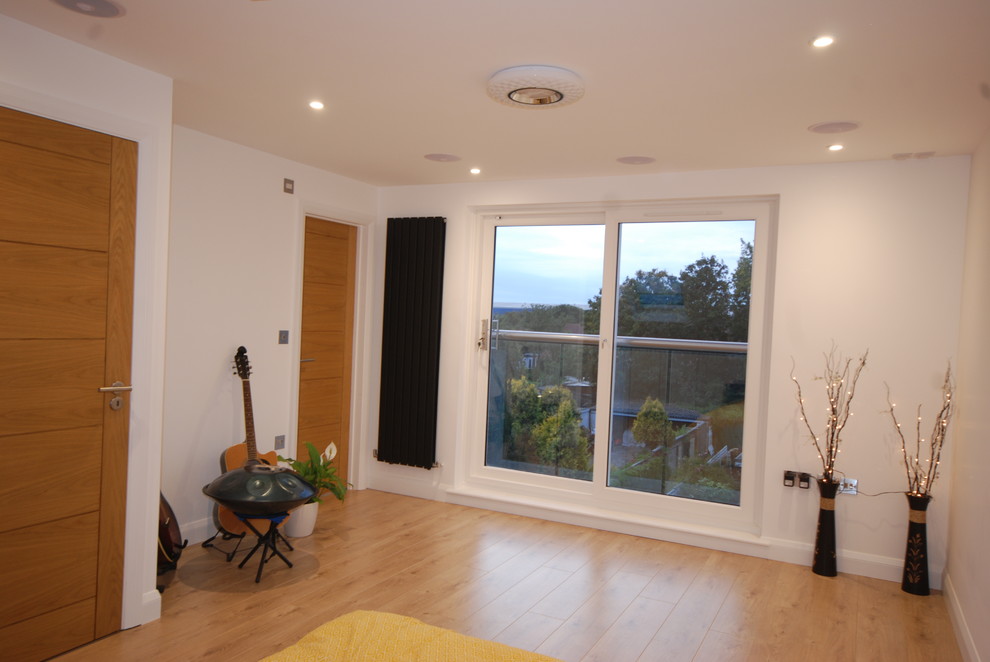Cette photo montre une chambre parentale tendance de taille moyenne avec un mur blanc, parquet clair et un sol marron.