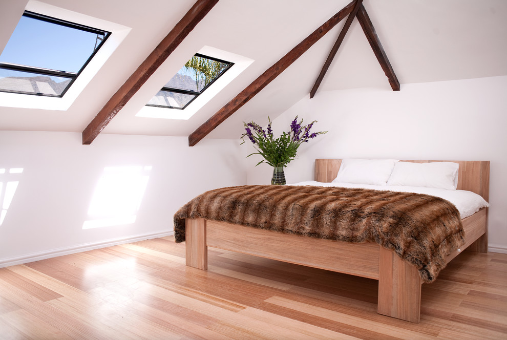 Exemple d'une chambre tendance avec un mur blanc et un sol en bois brun.