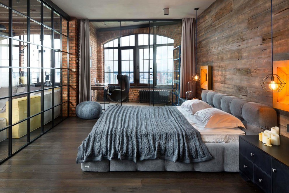 На фото: спальня на мансарде в стиле лофт с темным паркетным полом с