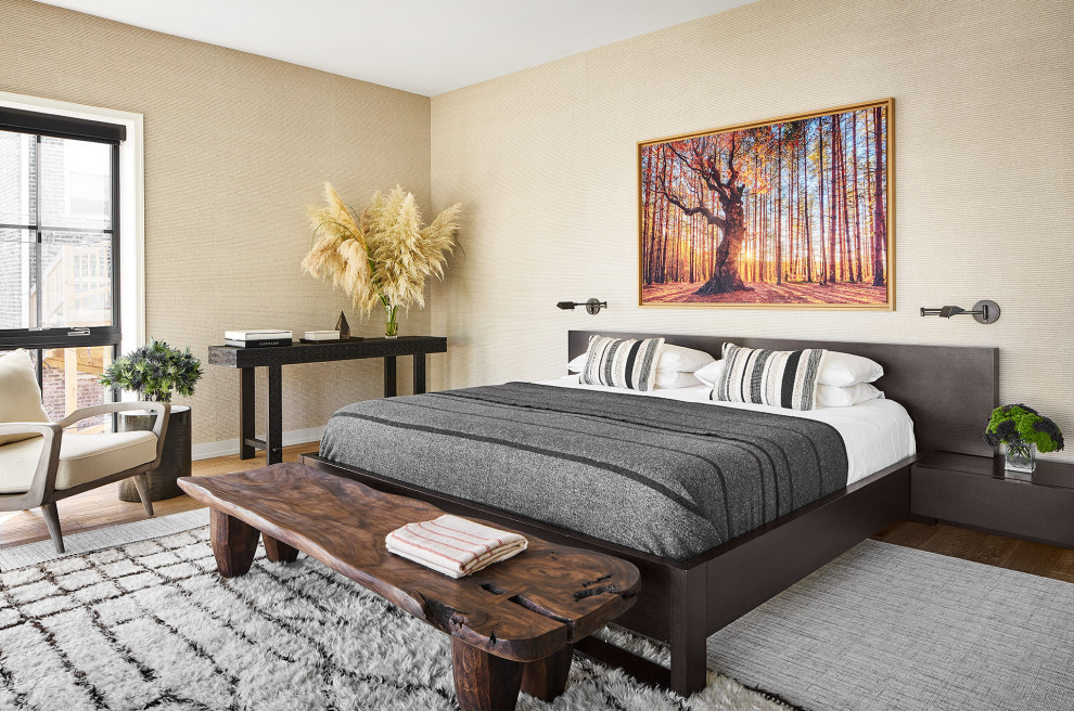 Cette image montre une grande chambre parentale design avec un mur beige, un sol en bois brun, un sol marron et du papier peint.