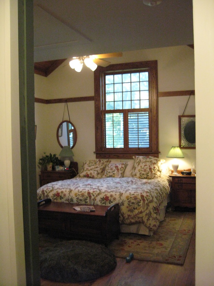 Cette image montre une chambre parentale de taille moyenne avec un mur blanc, un sol en bois brun, aucune cheminée et un sol marron.