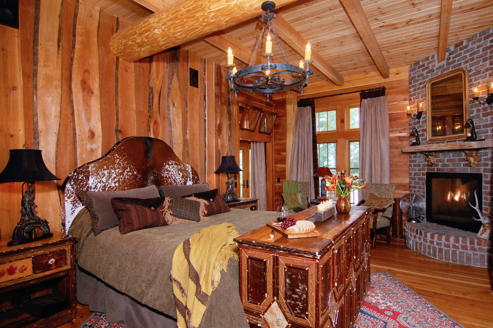 Imagen de dormitorio principal rústico de tamaño medio con paredes marrones, suelo de madera en tonos medios, chimenea de esquina y marco de chimenea de ladrillo