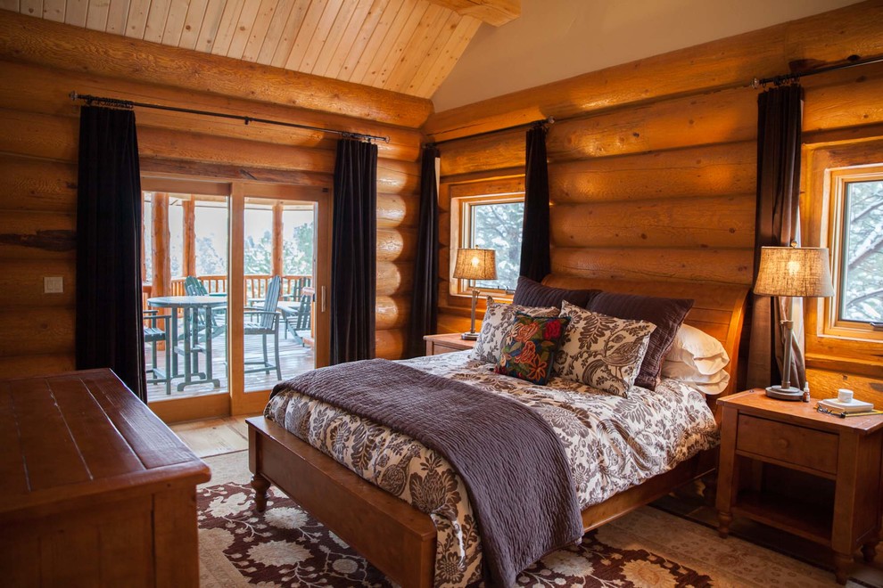 Diseño de dormitorio principal rural grande sin chimenea con paredes marrones, suelo de madera en tonos medios y suelo marrón