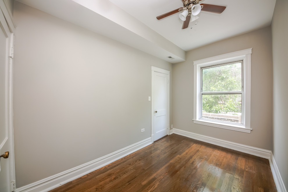 Ejemplo de habitación de invitados pequeña con paredes grises, suelo de madera en tonos medios y suelo marrón