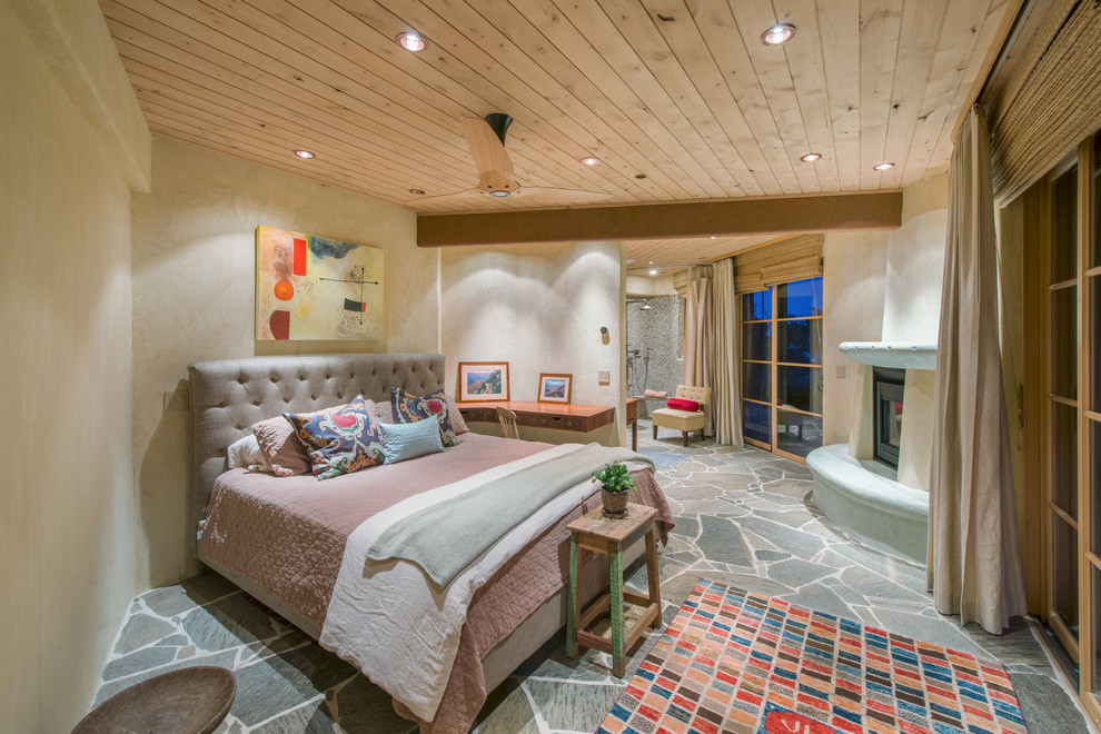Immagine di una camera da letto american style con pareti beige e camino ad angolo