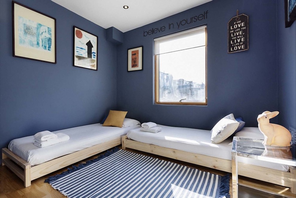Imagen de habitación de invitados actual de tamaño medio con paredes azules, suelo de madera clara y suelo marrón