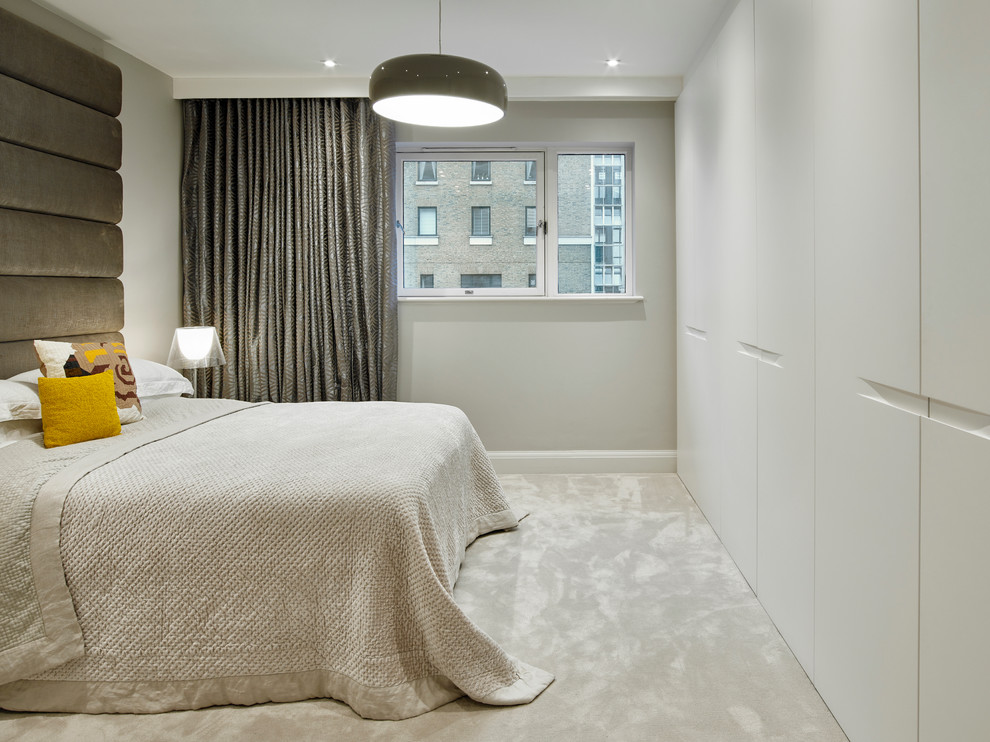 This is an example of a medium sized contemporary master bedroom in London with grey walls and carpet.