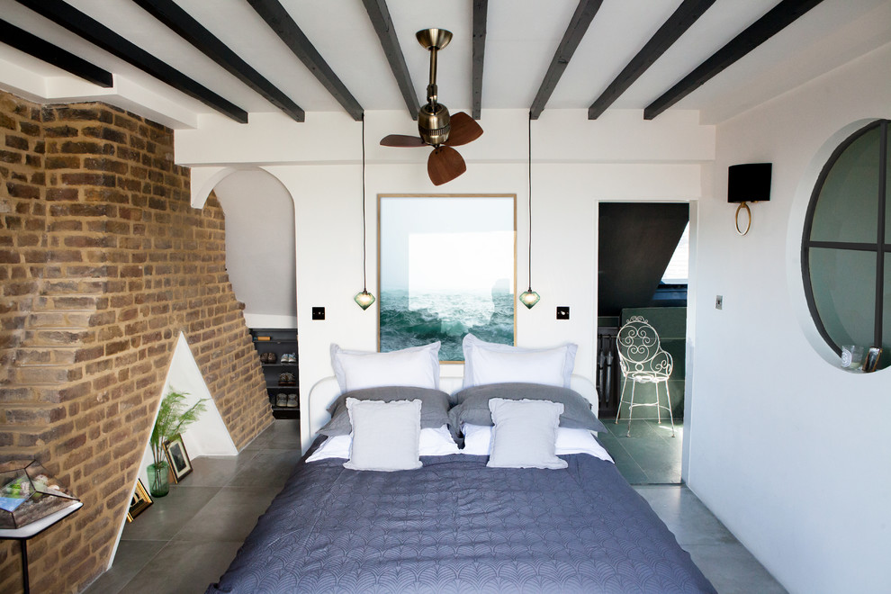 Mittelgroßes Industrial Schlafzimmer ohne Kamin mit weißer Wandfarbe, grauem Boden und Kaminumrandung aus Backstein in London