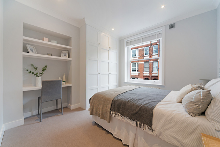 Small contemporary master bedroom in London with grey walls, carpet and beige floors.