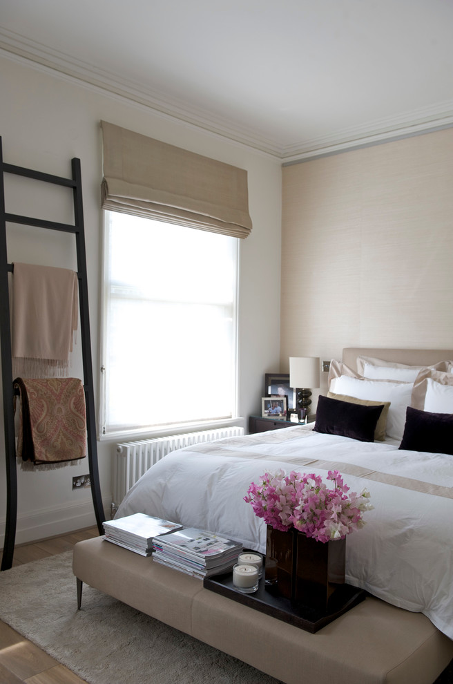 This is an example of a contemporary master bedroom in London with white walls and medium hardwood flooring.