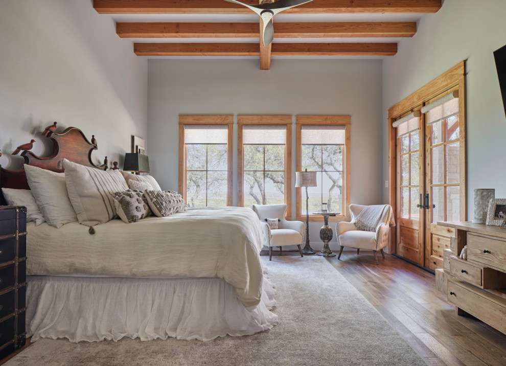 Country Schlafzimmer mit grauer Wandfarbe, braunem Holzboden, braunem Boden und freigelegten Dachbalken in Sonstige