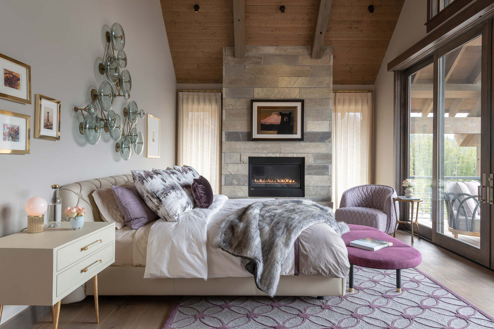 Idée de décoration pour une chambre parentale chalet avec un mur blanc, parquet clair, une cheminée ribbon, un manteau de cheminée en pierre et un plafond en bois.