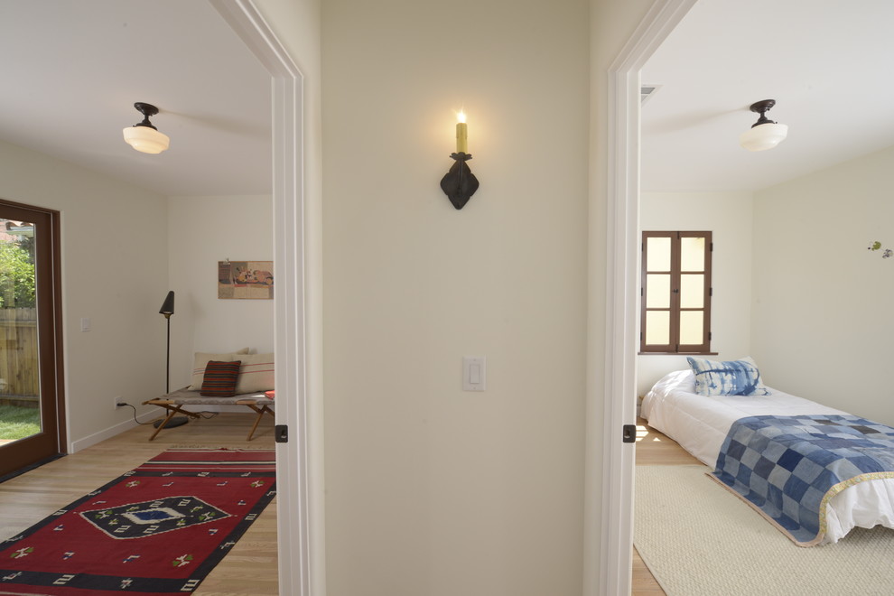 This is an example of a medium sized mediterranean guest bedroom in Los Angeles with white walls and light hardwood flooring.