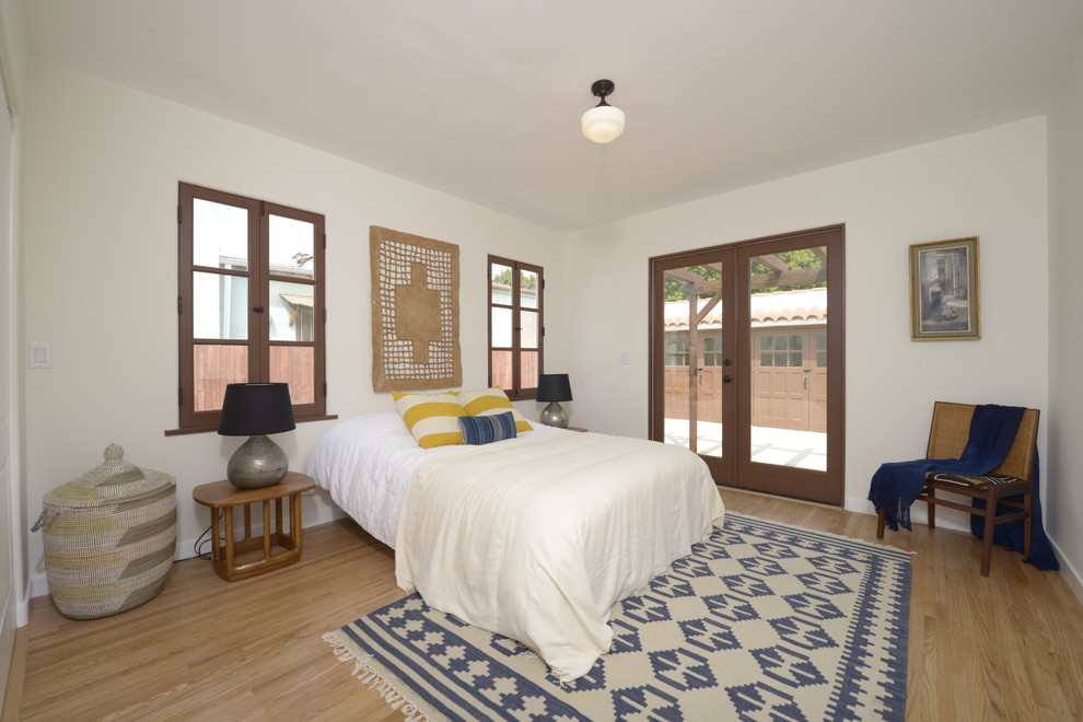 Diseño de dormitorio principal mediterráneo de tamaño medio con paredes blancas y suelo de madera clara