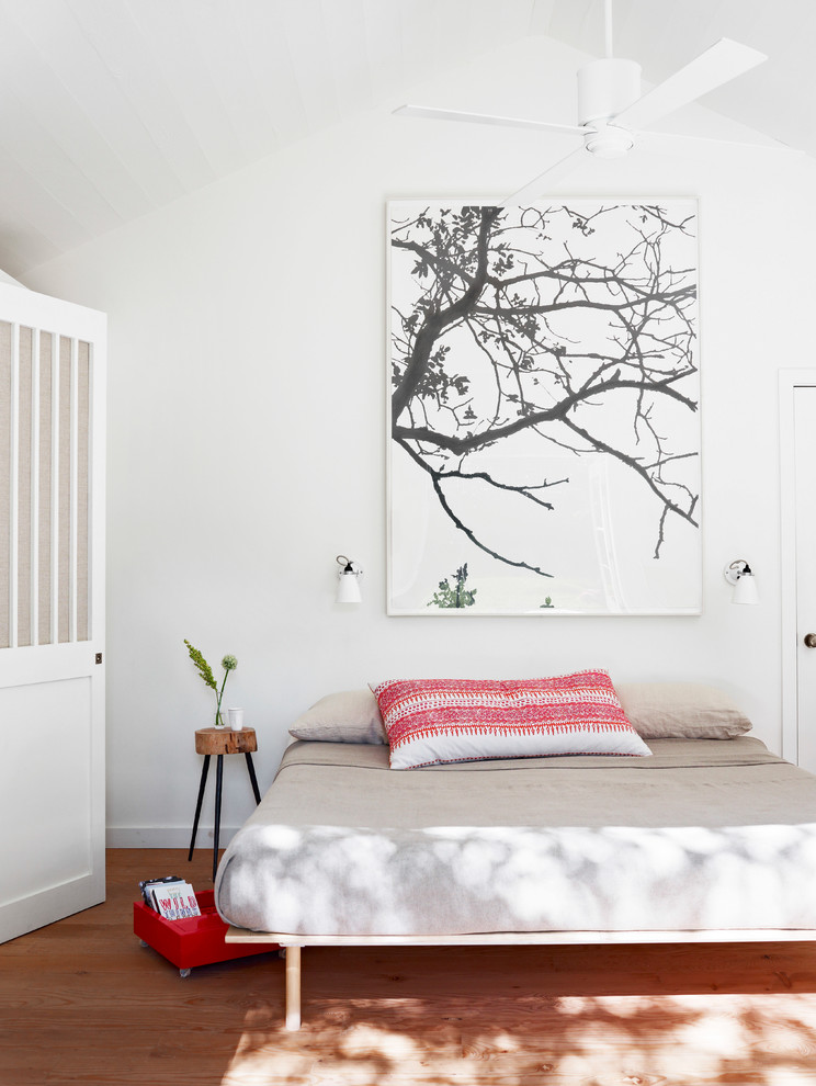 Foto di una camera da letto costiera con pareti bianche, pavimento in legno massello medio e nessun camino