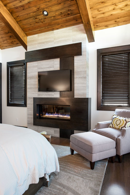 Diseño de dormitorio principal actual de tamaño medio con paredes blancas, suelo de madera oscura, chimenea lineal y marco de chimenea de baldosas y/o azulejos