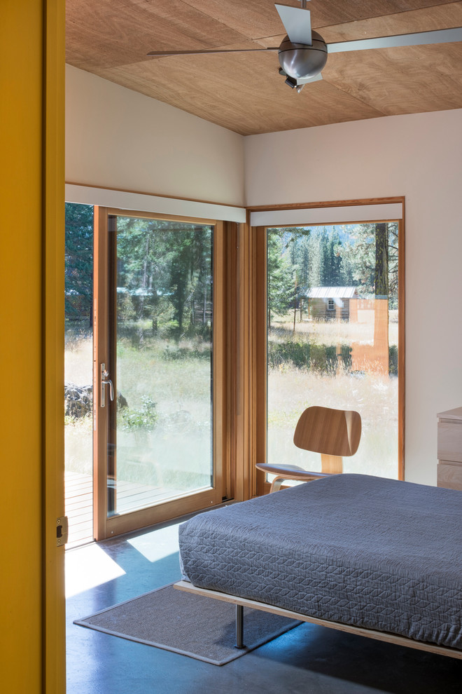 Imagen de habitación de invitados contemporánea pequeña con paredes beige y suelo de cemento
