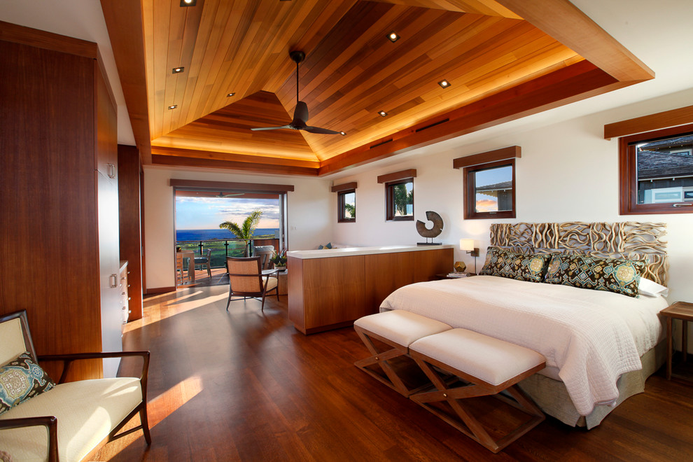Großes Hauptschlafzimmer ohne Kamin mit weißer Wandfarbe und dunklem Holzboden in Hawaii