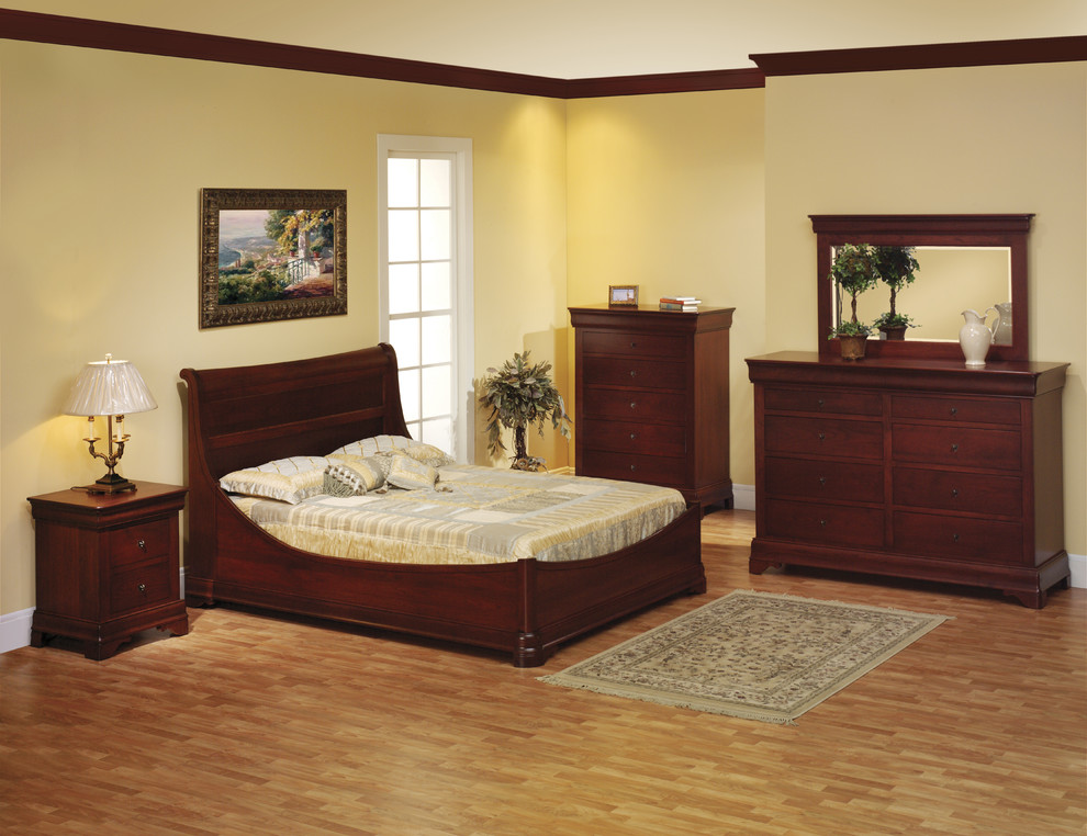 Modelo de dormitorio principal grande sin chimenea con paredes amarillas y suelo de madera clara