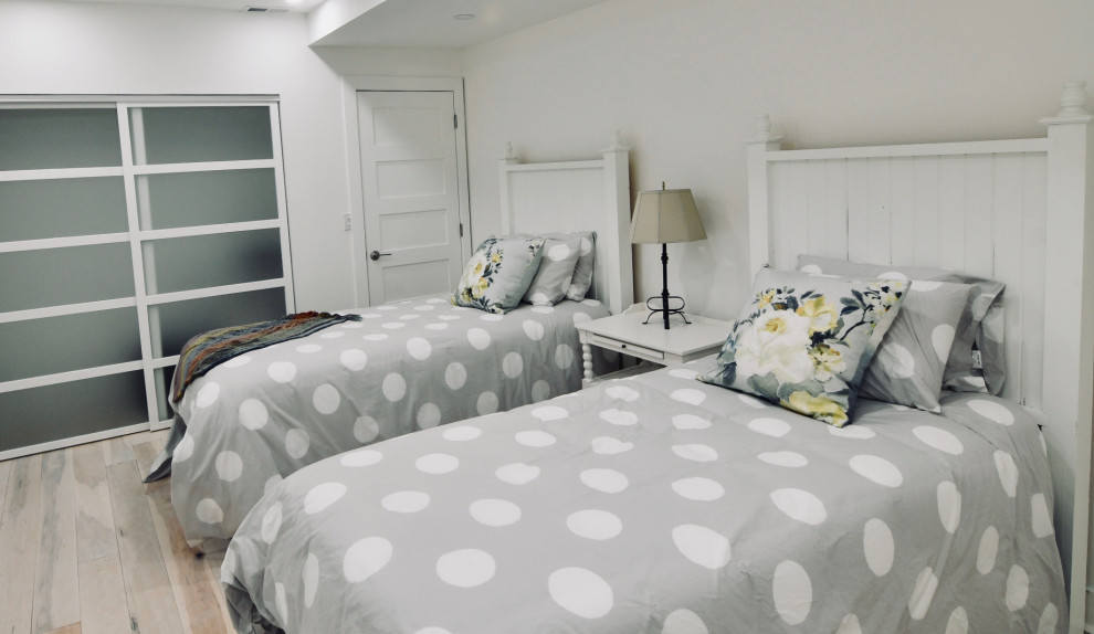 Ejemplo de habitación de invitados costera de tamaño medio con paredes blancas, suelo de madera clara y suelo beige