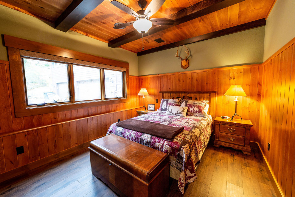 На фото: гостевая спальня (комната для гостей) в стиле рустика с зелеными стенами, полом из ламината и деревянным потолком