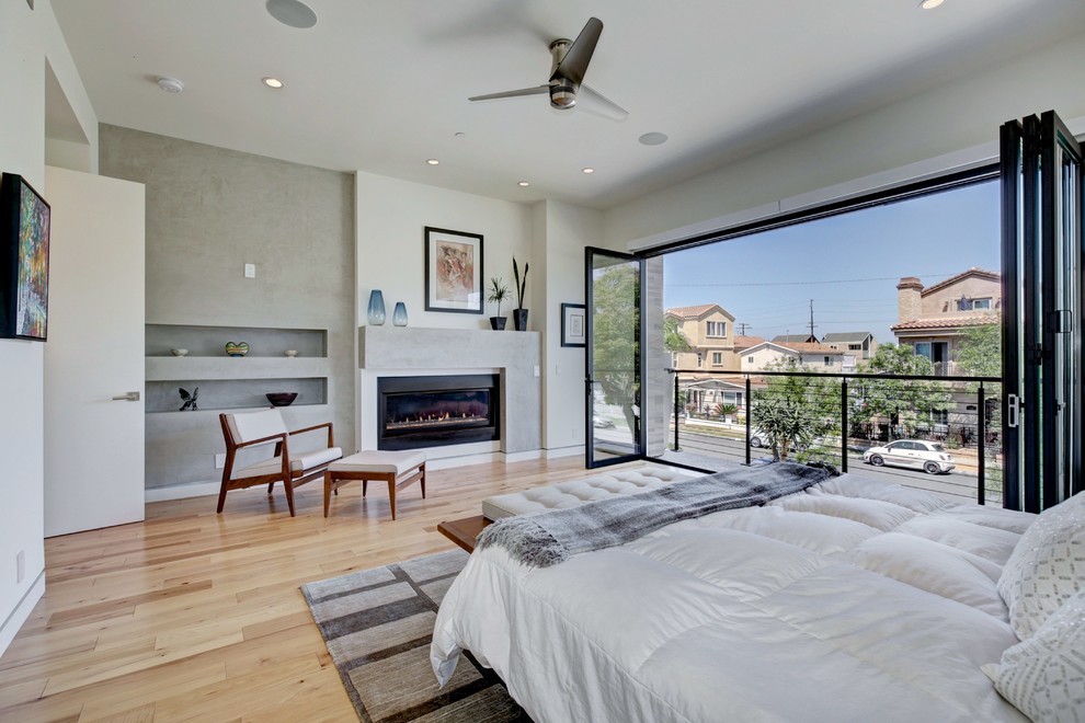 Modernes Hauptschlafzimmer mit weißer Wandfarbe, Gaskamin und hellem Holzboden in Orange County