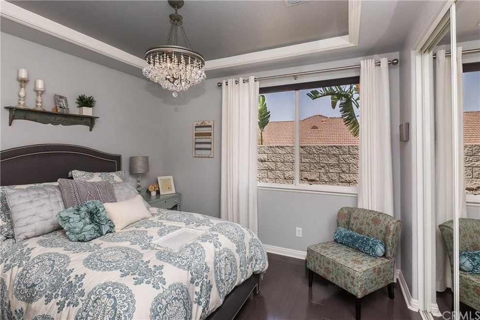 Ejemplo de habitación de invitados clásica renovada pequeña con paredes grises y suelo de madera en tonos medios