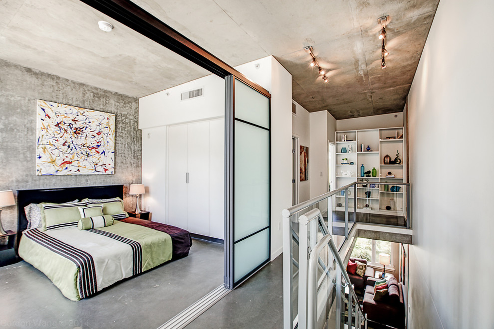 Esempio di una camera da letto stile loft industriale di medie dimensioni con pareti grigie, pavimento in cemento e nessun camino