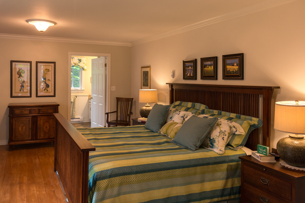 Modelo de dormitorio principal tradicional con paredes beige y suelo de madera clara