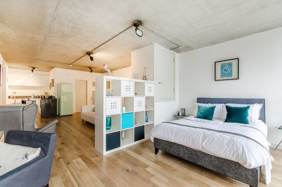 Cette photo montre une petite chambre tendance avec un mur blanc et un sol en bois brun.