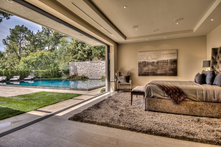Cette image montre une grande chambre parentale minimaliste avec un mur beige et un sol en calcaire.