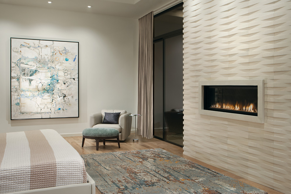 Großes Modernes Hauptschlafzimmer mit weißer Wandfarbe, hellem Holzboden, Gaskamin, Kaminumrandung aus Stein und beigem Boden in Phoenix