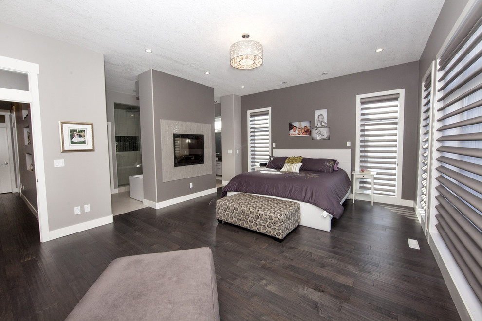 Modernes Hauptschlafzimmer mit dunklem Holzboden, grauer Wandfarbe, Tunnelkamin und Kaminumrandung aus Stein in Edmonton
