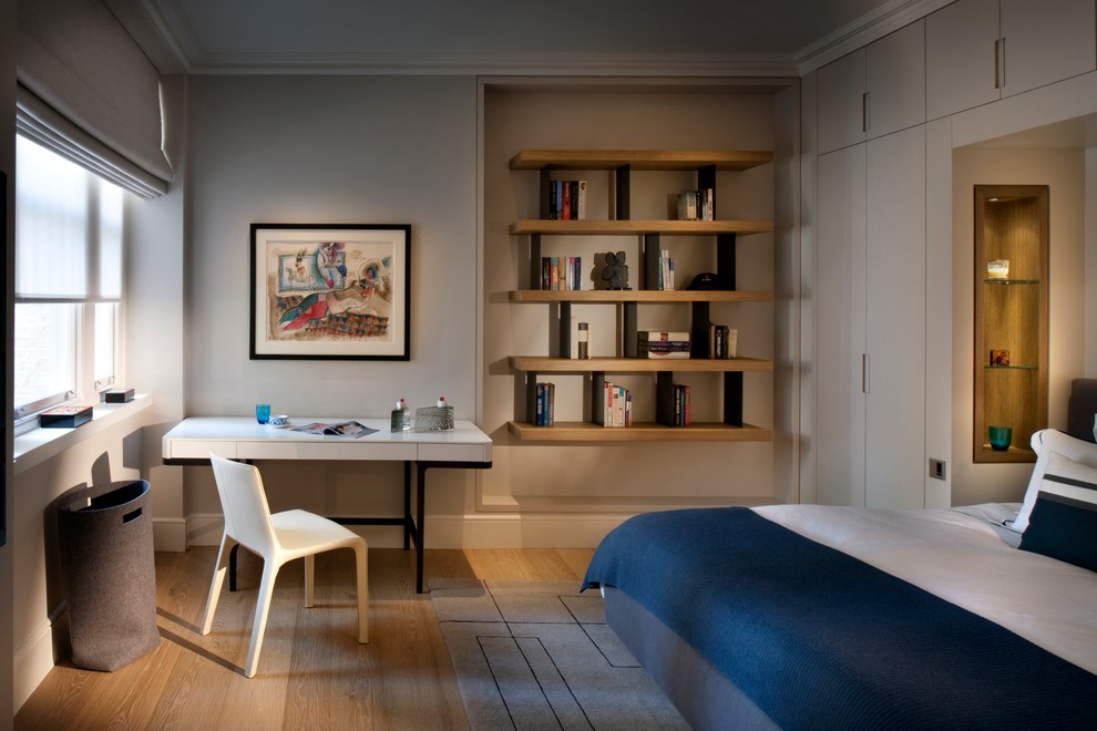 Diseño de dormitorio contemporáneo con paredes grises, suelo de madera clara y con escritorio