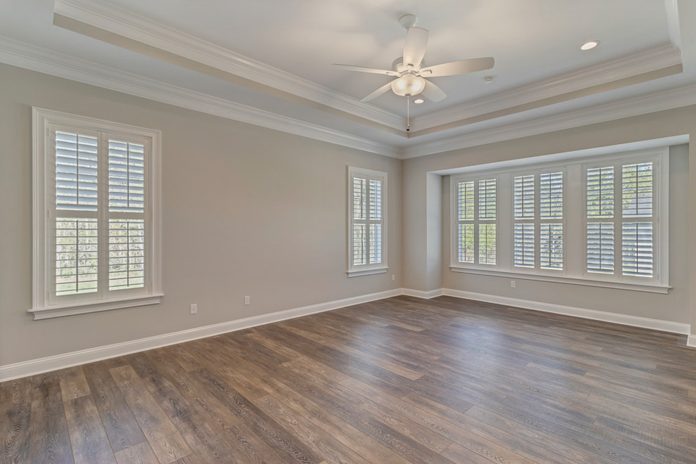 Design ideas for a large farmhouse master bedroom in Jacksonville with white walls, vinyl flooring and brown floors.
