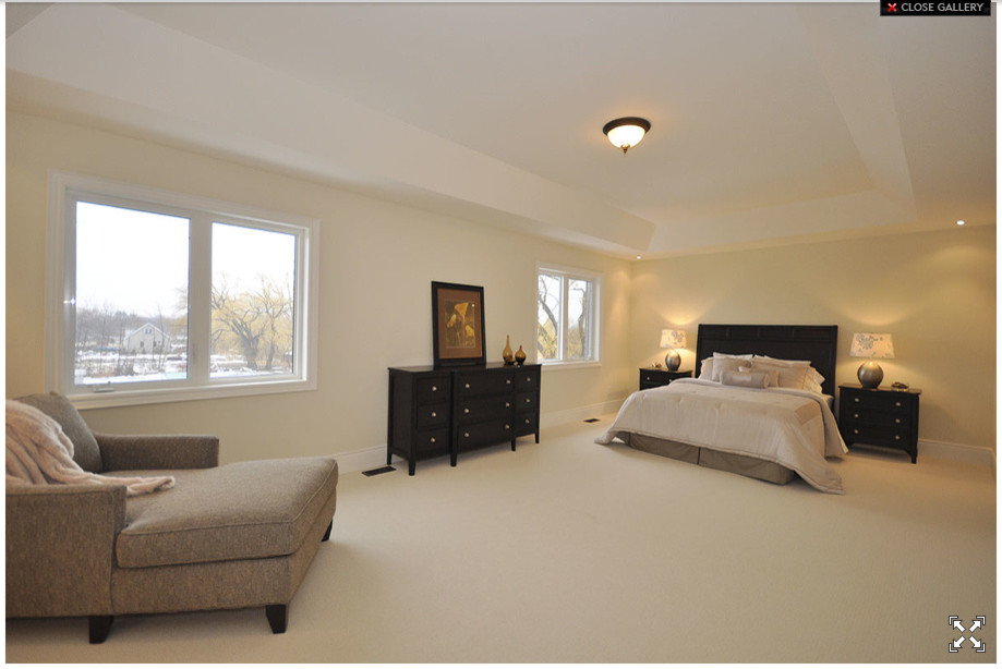 This is an example of a large contemporary master bedroom in Toronto with beige walls and carpet.