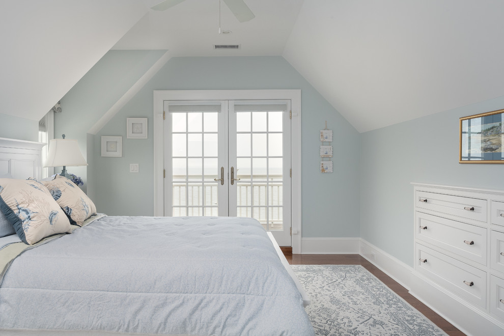 Imagen de dormitorio costero grande con paredes azules, suelo de madera en tonos medios y todas las chimeneas