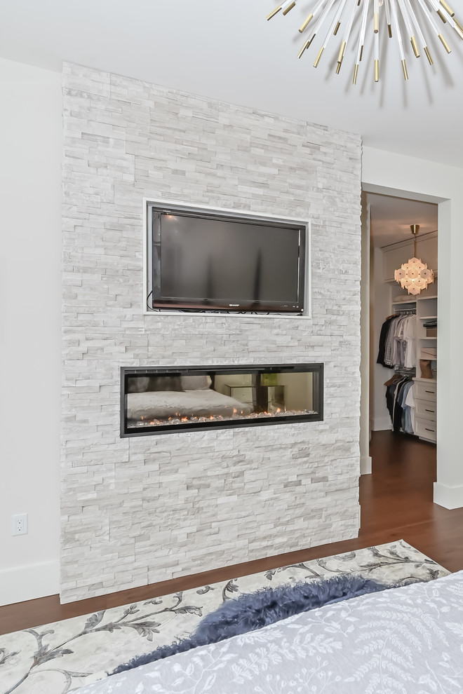 Mittelgroßes Modernes Hauptschlafzimmer mit grauer Wandfarbe, Hängekamin und Kaminumrandung aus Stein in Toronto