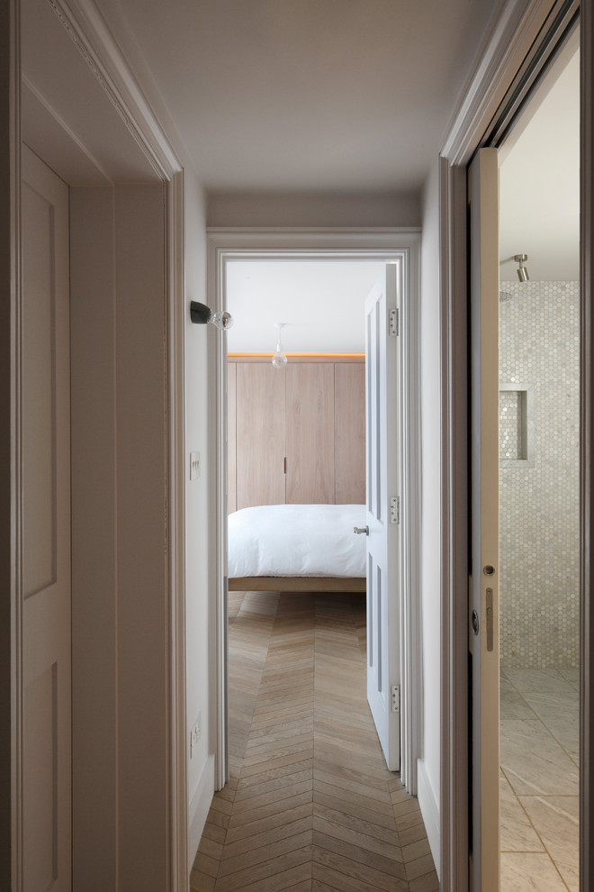 Esempio di una grande camera degli ospiti minimal con pareti bianche, parquet chiaro e pavimento marrone
