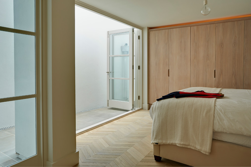 Imagen de habitación de invitados actual grande con paredes blancas, suelo de madera clara y suelo marrón