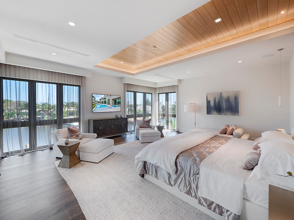 Geräumiges Modernes Hauptschlafzimmer mit weißer Wandfarbe, braunem Holzboden und braunem Boden in Miami