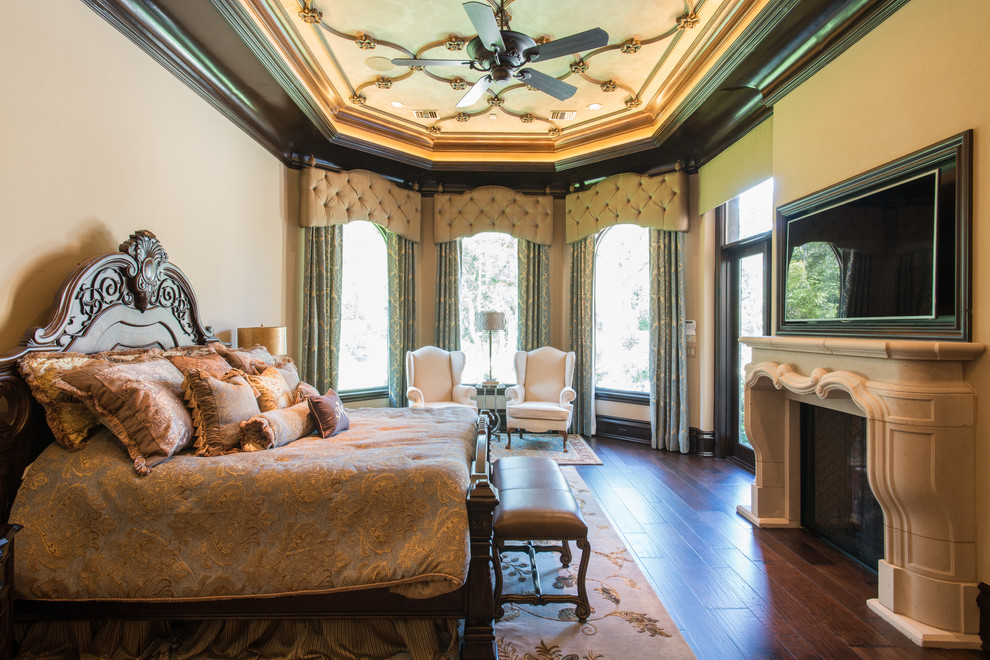 ヒューストンにあるヴィクトリアン調のおしゃれな主寝室 (ベージュの壁、濃色無垢フローリング、標準型暖炉、石材の暖炉まわり、茶色い床、折り上げ天井) のレイアウト