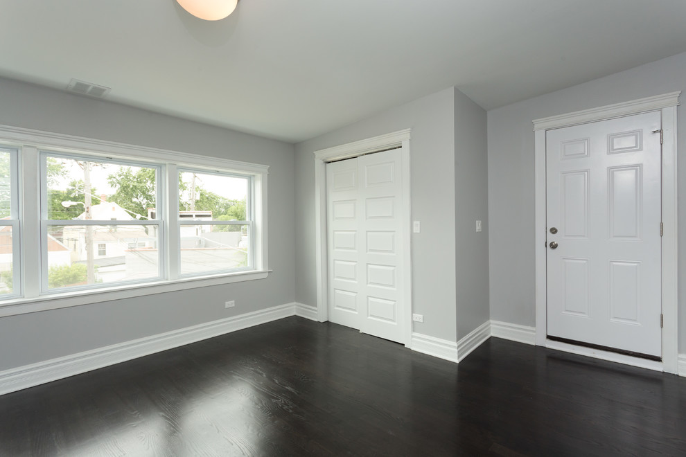 Mittelgroßes Modernes Schlafzimmer ohne Kamin mit grauer Wandfarbe, dunklem Holzboden und braunem Boden in Chicago