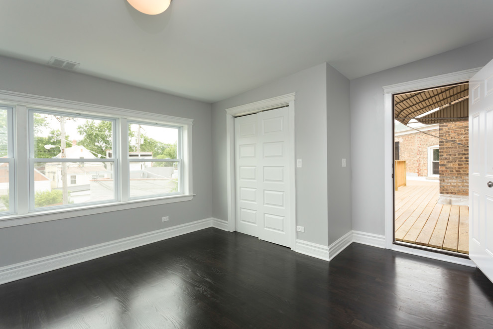 Cette photo montre une chambre tendance de taille moyenne avec un mur gris, parquet foncé, aucune cheminée et un sol marron.