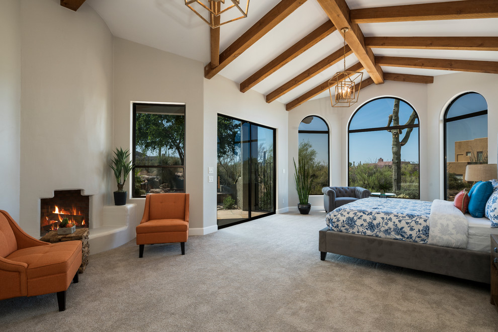 フェニックスにあるサンタフェスタイルのおしゃれな主寝室 (白い壁、カーペット敷き、コーナー設置型暖炉、漆喰の暖炉まわり、グレーの床)