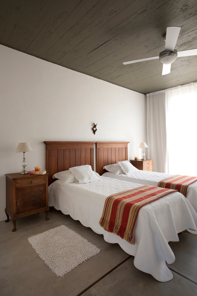 他の地域にあるコンテンポラリースタイルのおしゃれな寝室 (白い壁、コンクリートの床) のインテリア