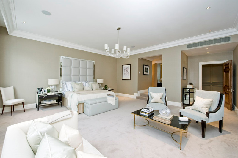 Expansive classic master and grey and cream bedroom in London with grey walls and carpet.